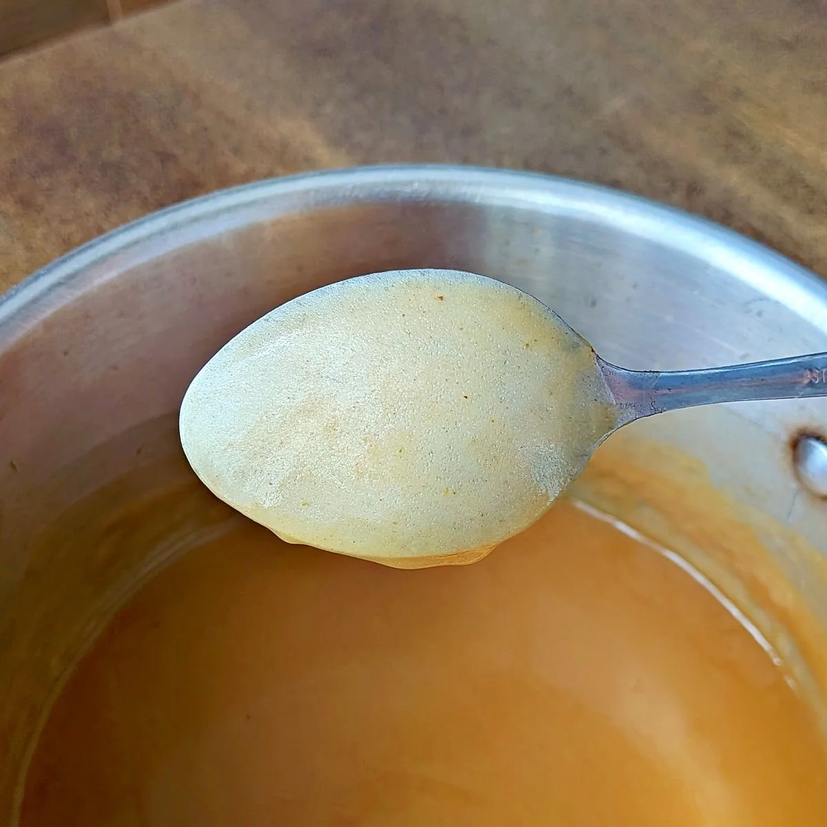 Gravy showing nappe consistency on the back of a spoon