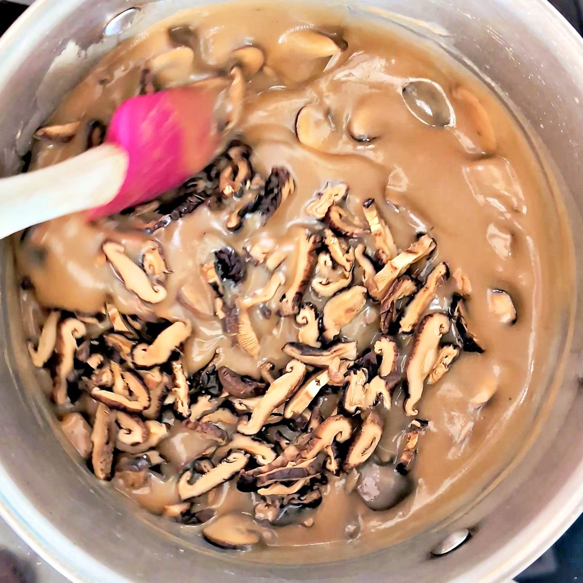 Adding sliced rehydrated shiitake mushrooms to the mushroom gravy