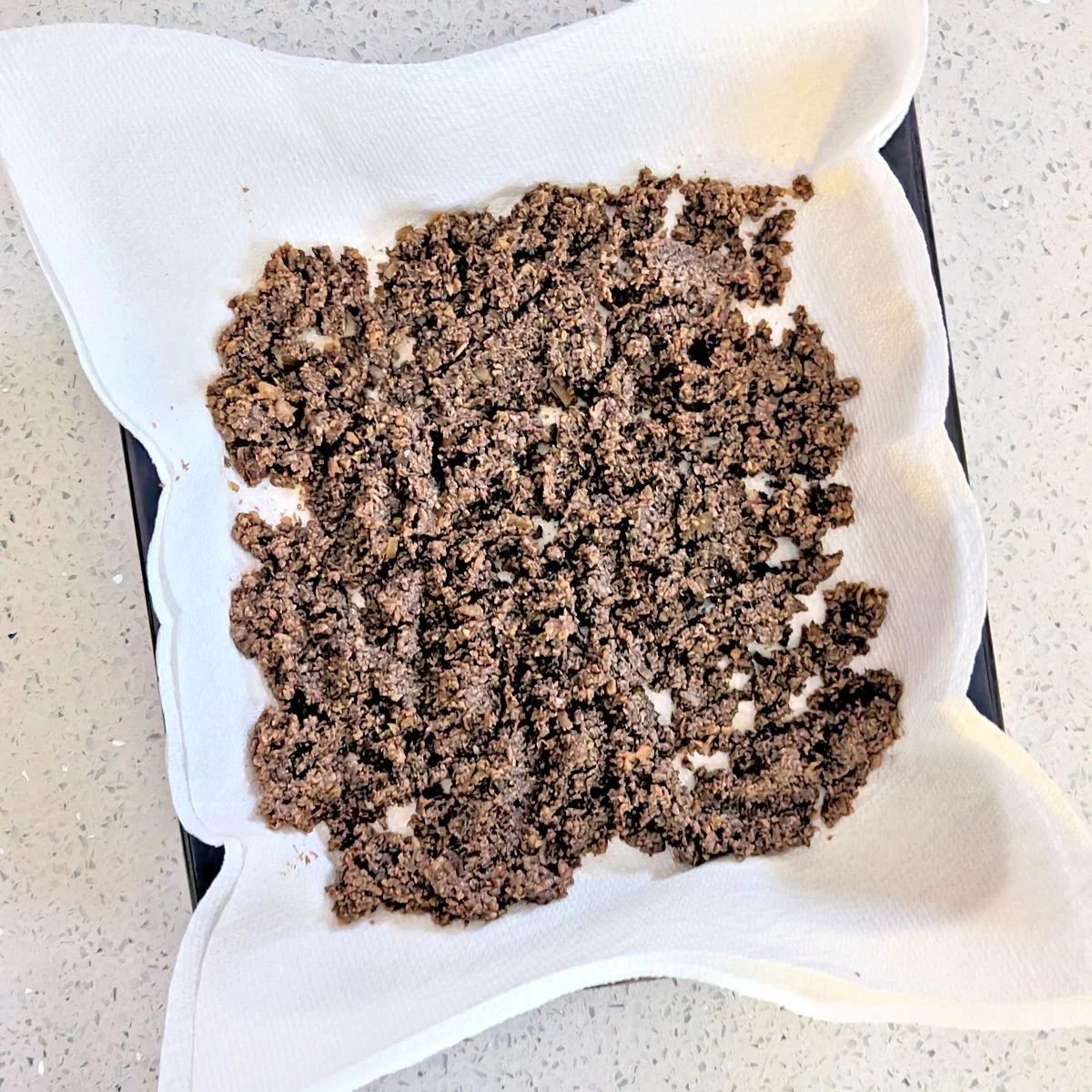 Cooked mushroom duxelles spread on paper towels to cool and remove excess moisture before wrapping the beef Wellington