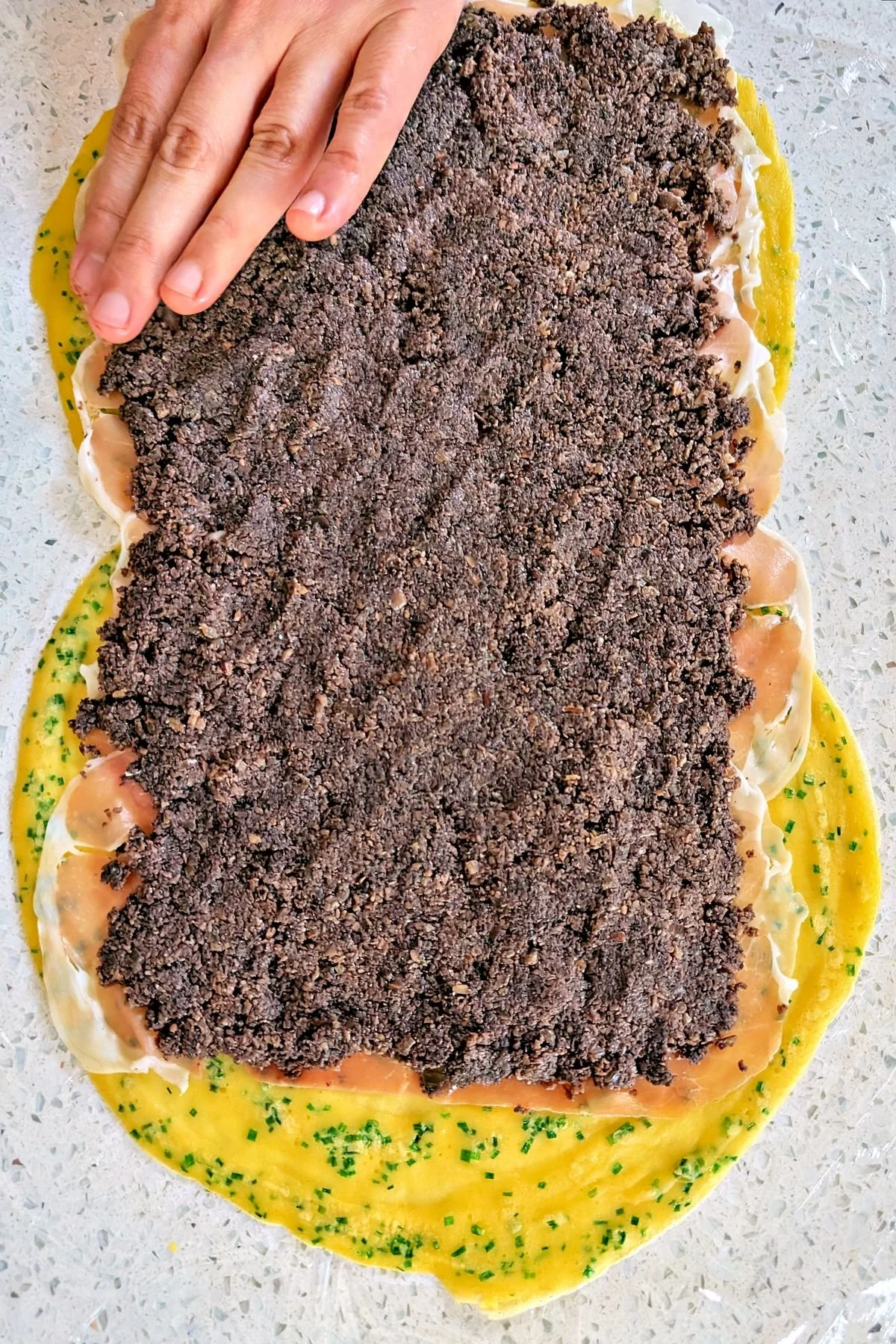 Mushroom duxelles spread over the prosciutto layer
