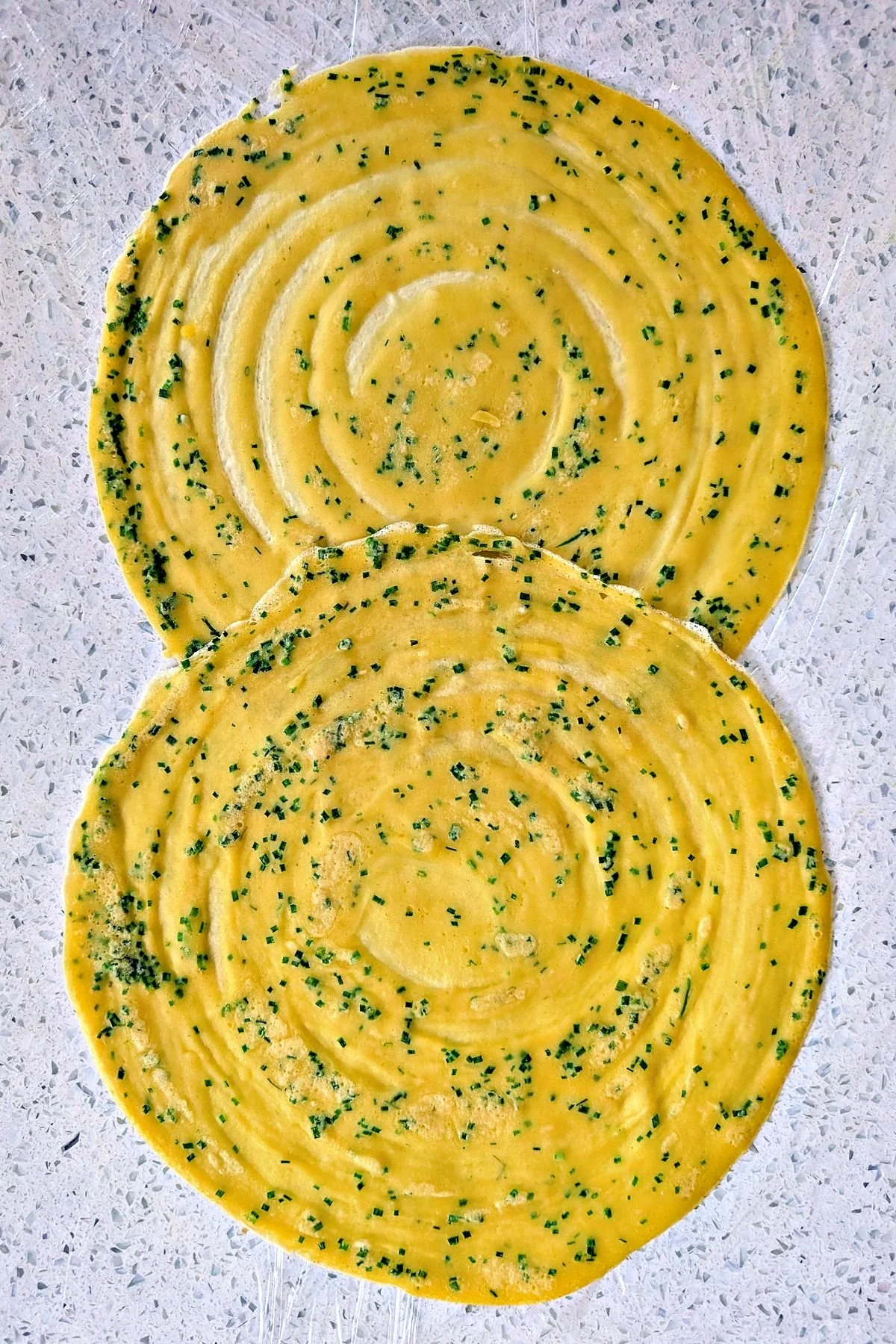 Chive crêpes overlapped on plastic wrap for beef Wellington