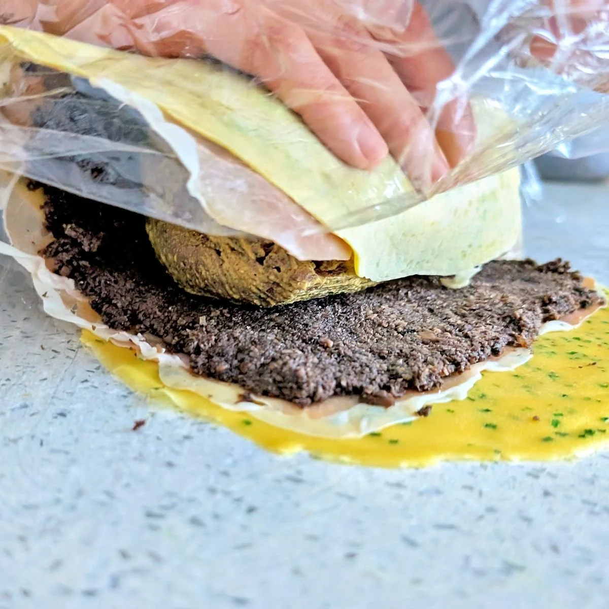 Crêpe and duxelles layers being rolled around the beef tenderloin