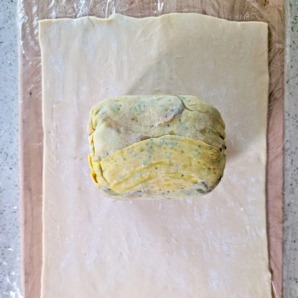 Chilled beef tenderloin wrapped in crêpe layer positioned on the puff pastry