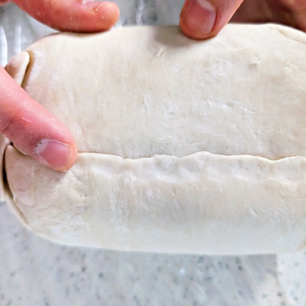 Puff pastry seam pressed closed along the bottom of the beef Wellington