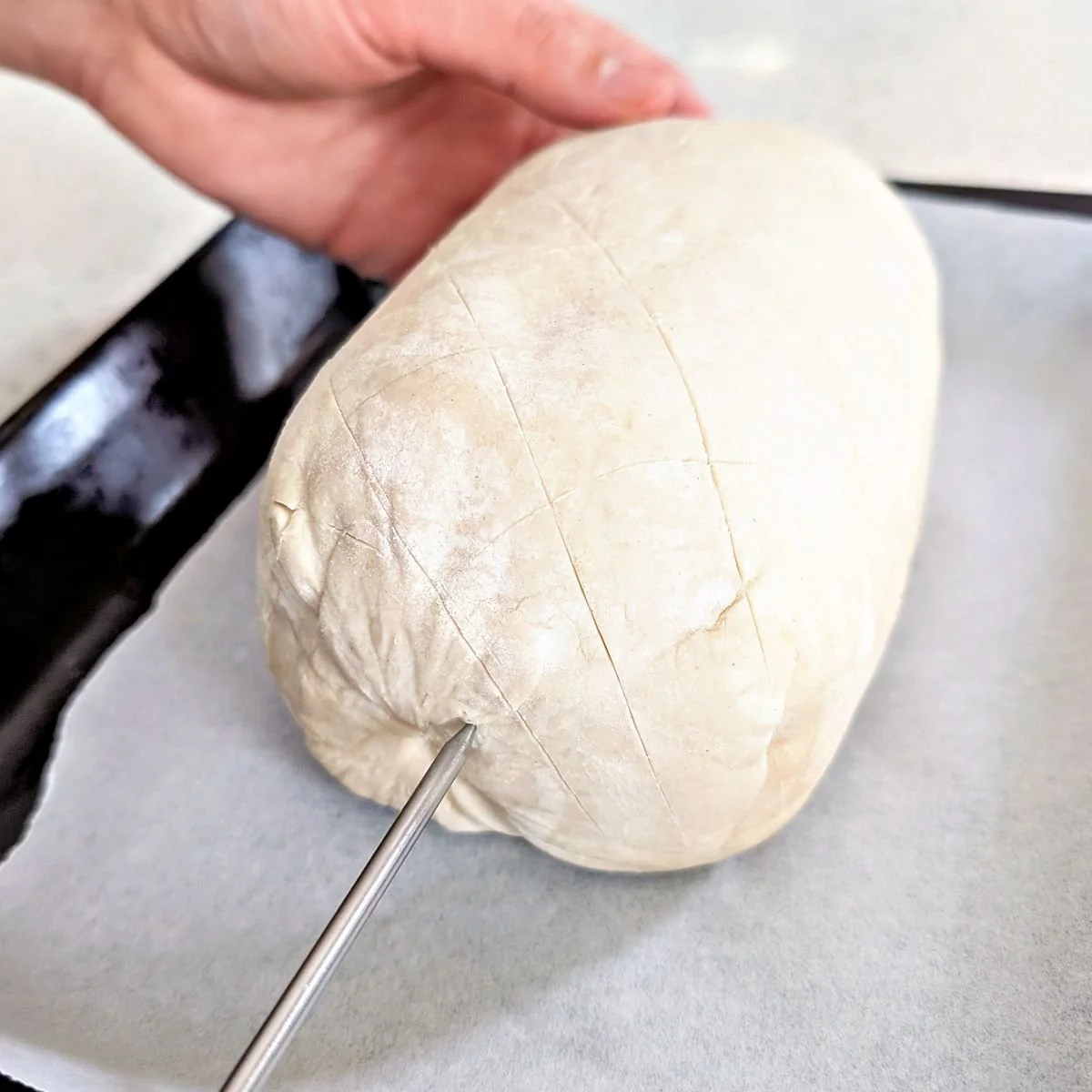 Oven-safe probe thermometer inserted into the end of beef Wellington