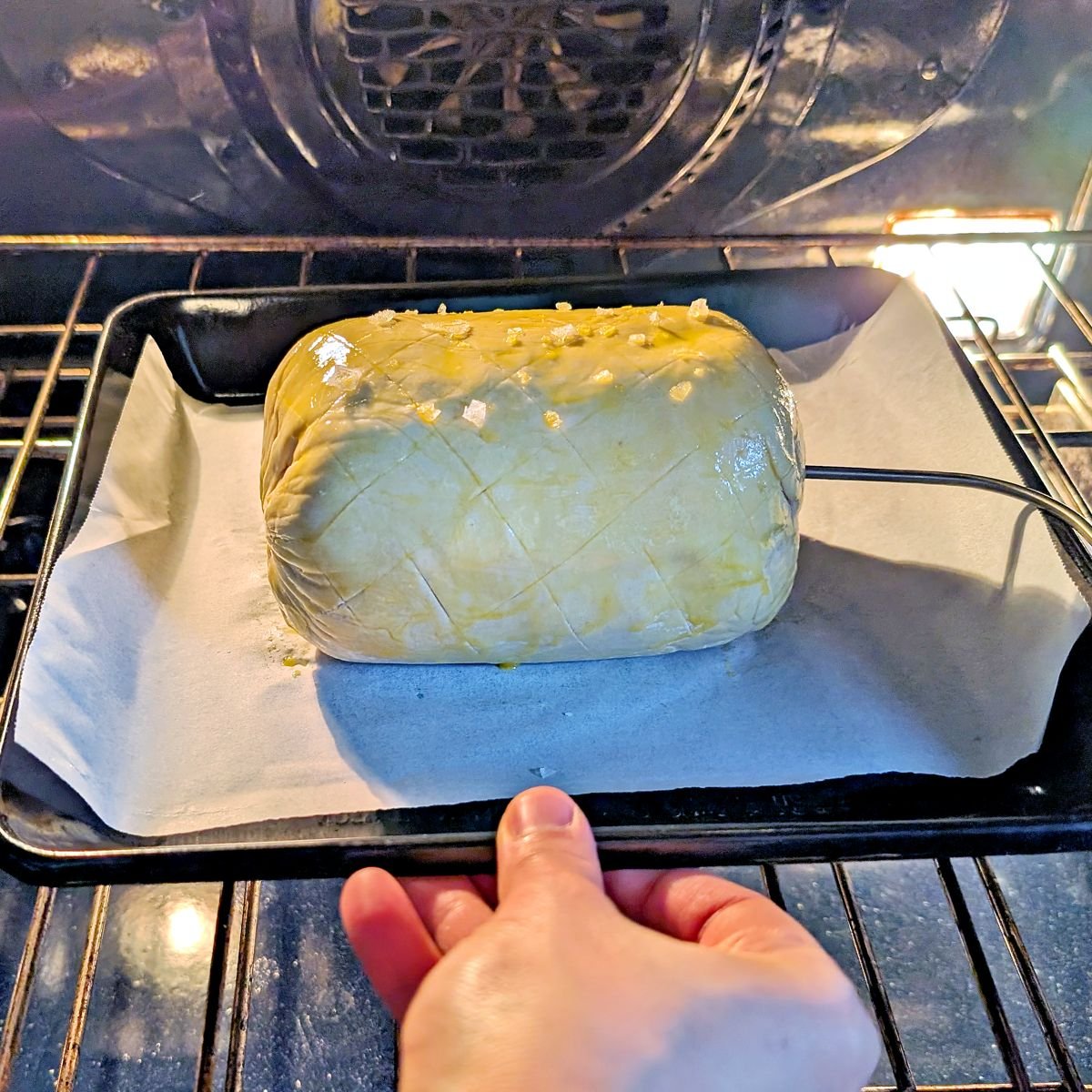 Beef Wellington placed in the oven with a probe thermometer