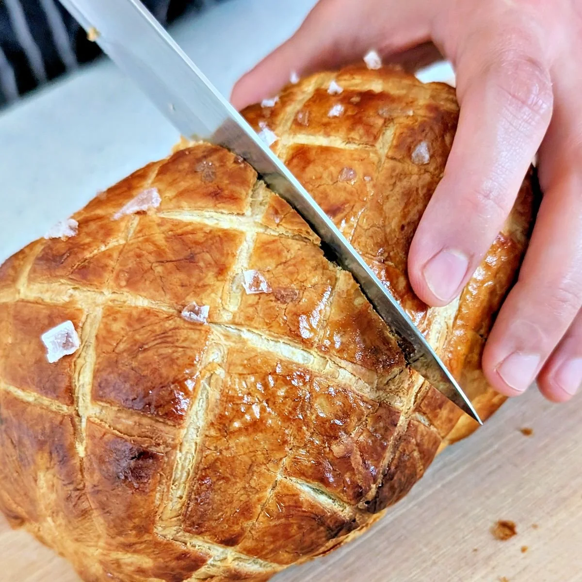 Rested beef Wellington being sliced with a sharp knife