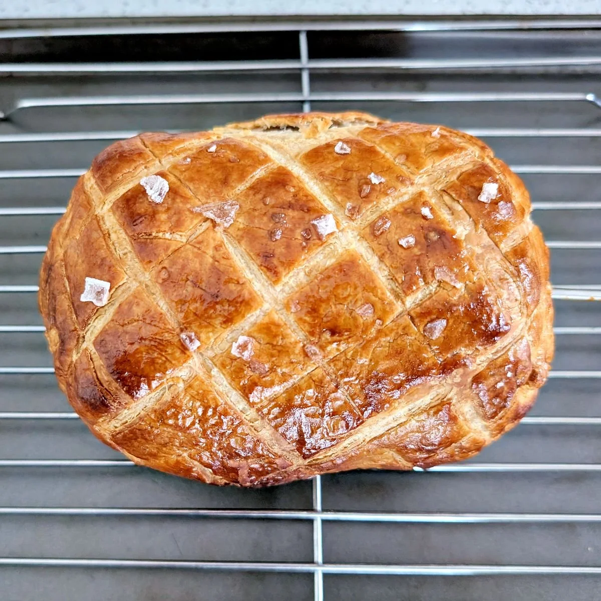 Baked beef Wellington resting on a wire cooling rack