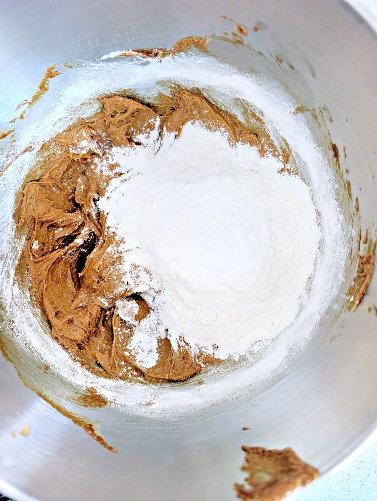 Flour added to the gingerbread cookie mixture in a stand mixer bowl