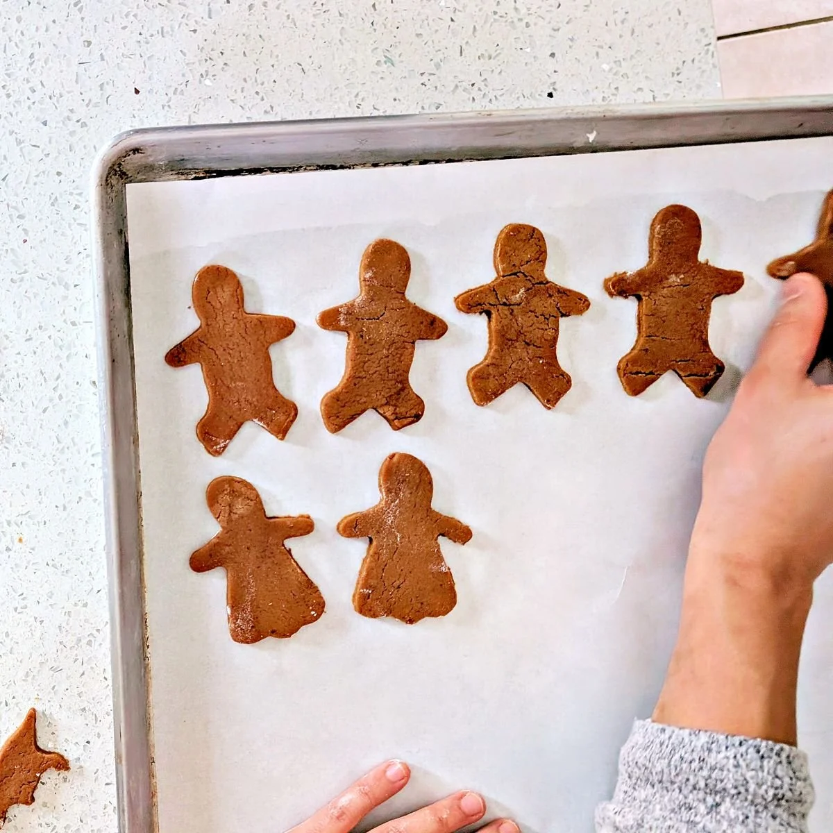 Cutout gingerbread cookies arranged on a parchment-lined baking sheet