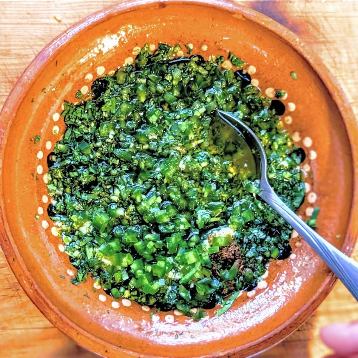 Middle Eastern zhoug sauce with a spoon in a clay bowl