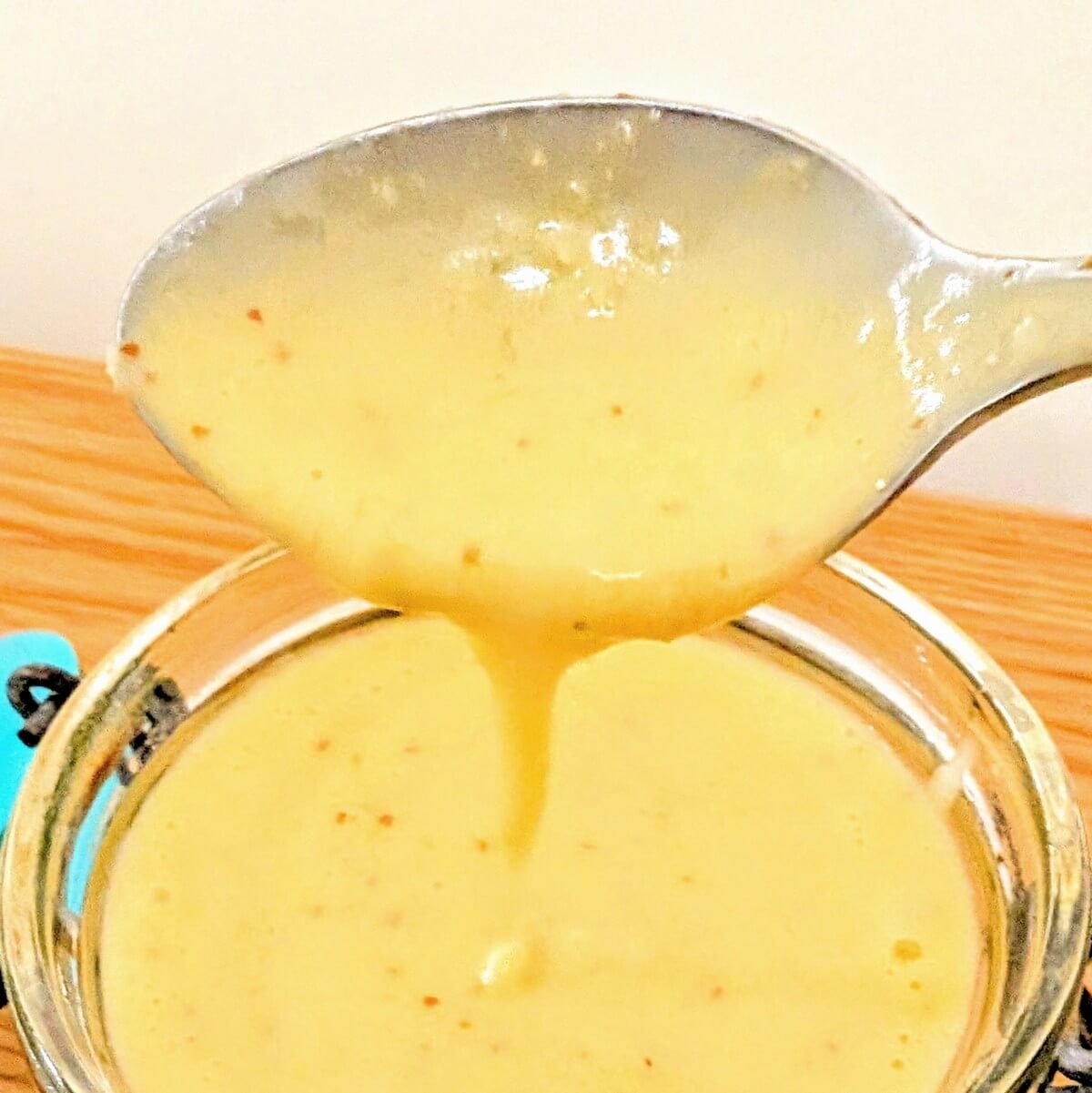 A spoon with preserved lemon vinaigrette over a jar of it