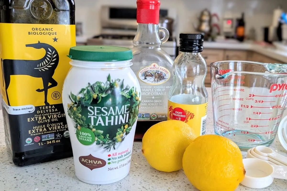 Tahini sauce ingredients, including sesame tahini paste, olive oil, maple syrup, sesame oil, lemon, and water