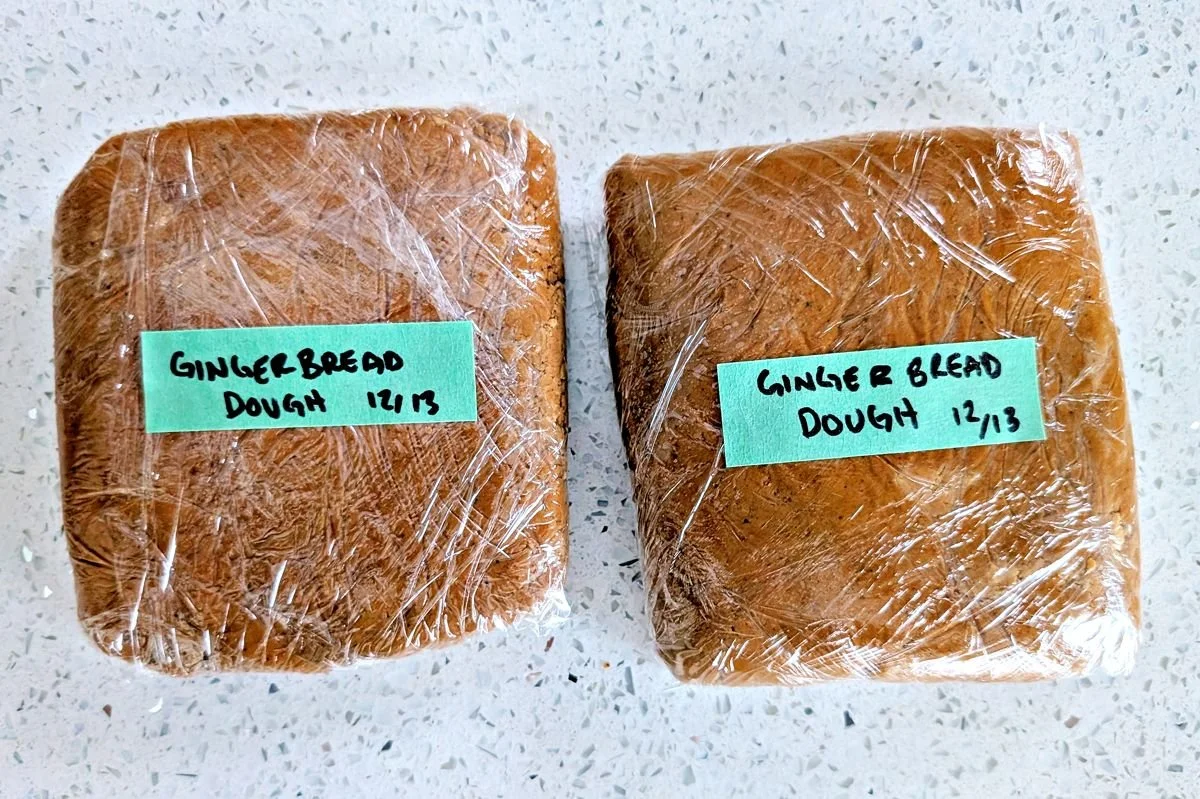 Two portions of gingerbread cookie dough wrapped and labeled for chilling