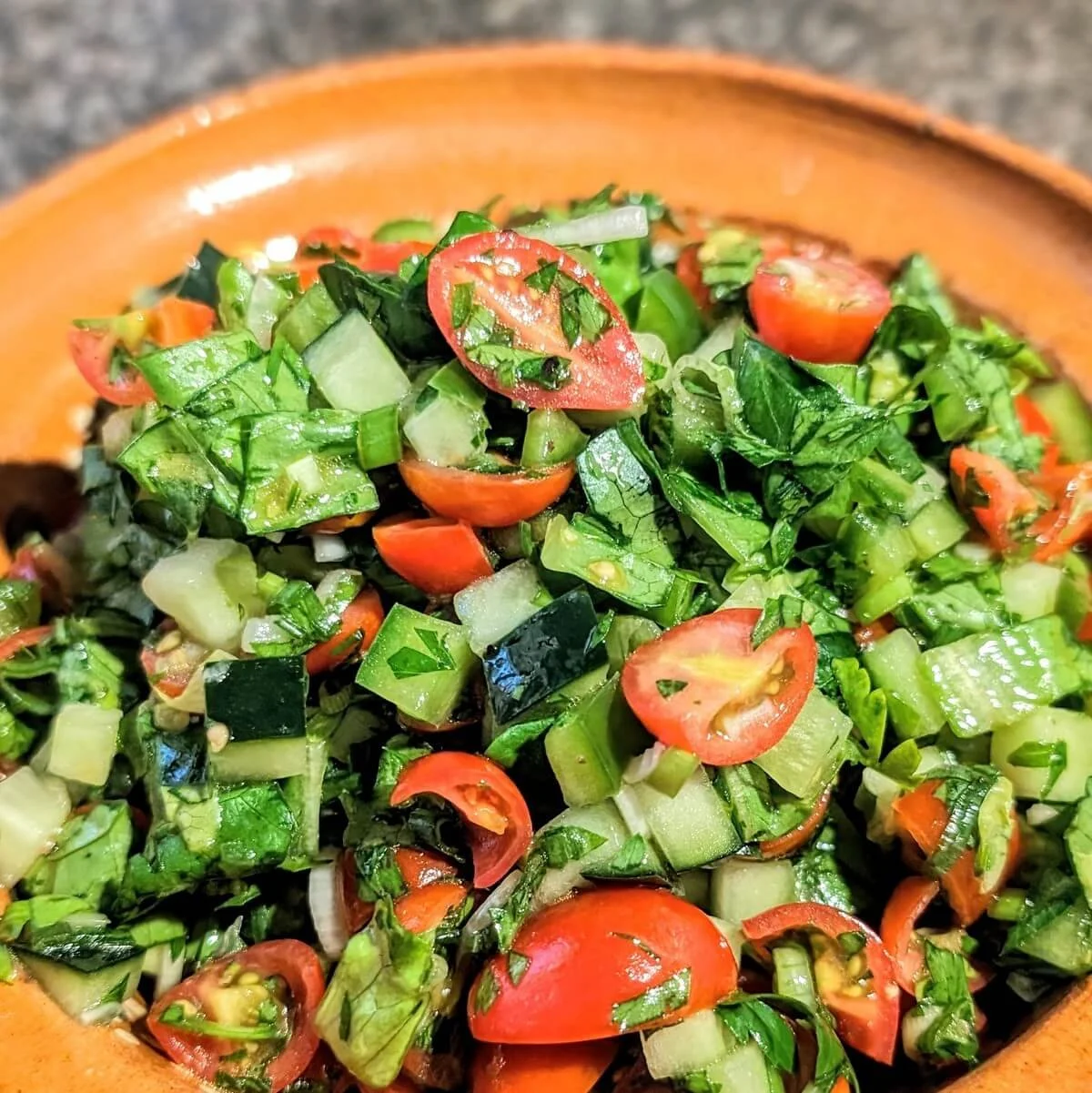 Middle Eastern chopped salad with finely diced cucumber, tomato, and herbs in a clay bowl