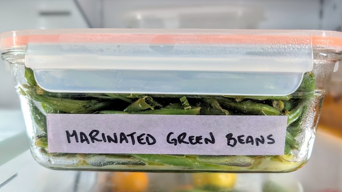 Marinated green beans in a glass storage container, prepped ahead and chilling in the fridge for Christmas dinner