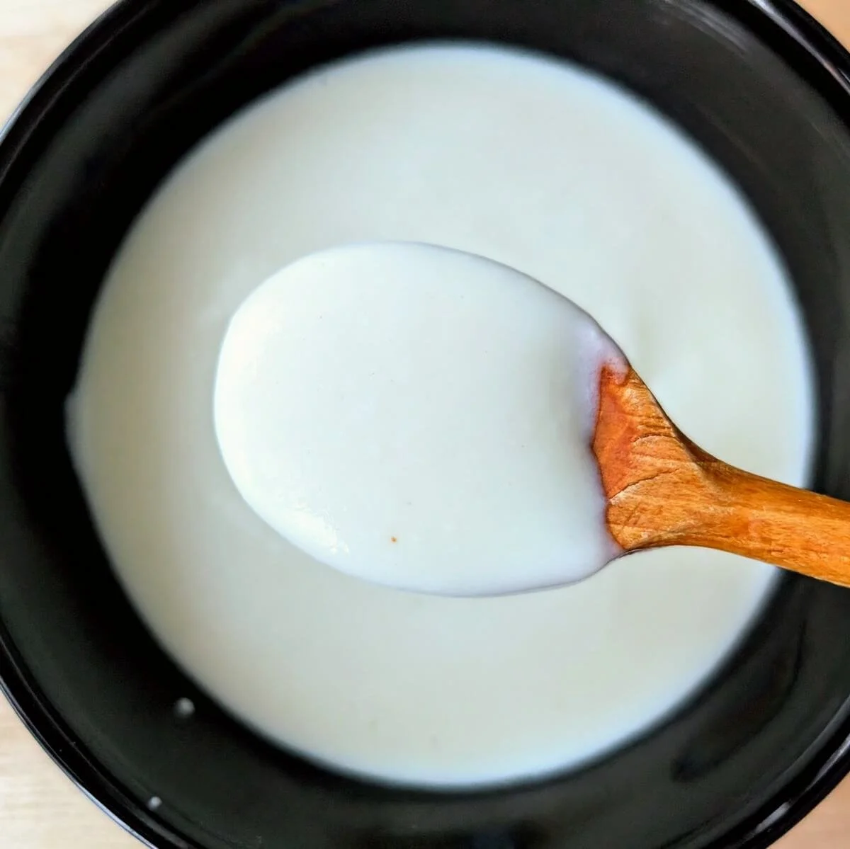Creamy bechamel sauce in a bowl with a wooden spoon, showing classic bechamel texture