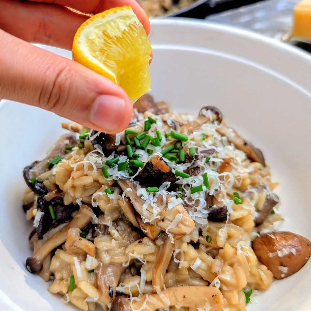 Fresh lemon being squeezed over creamy mushroom risotto at camp