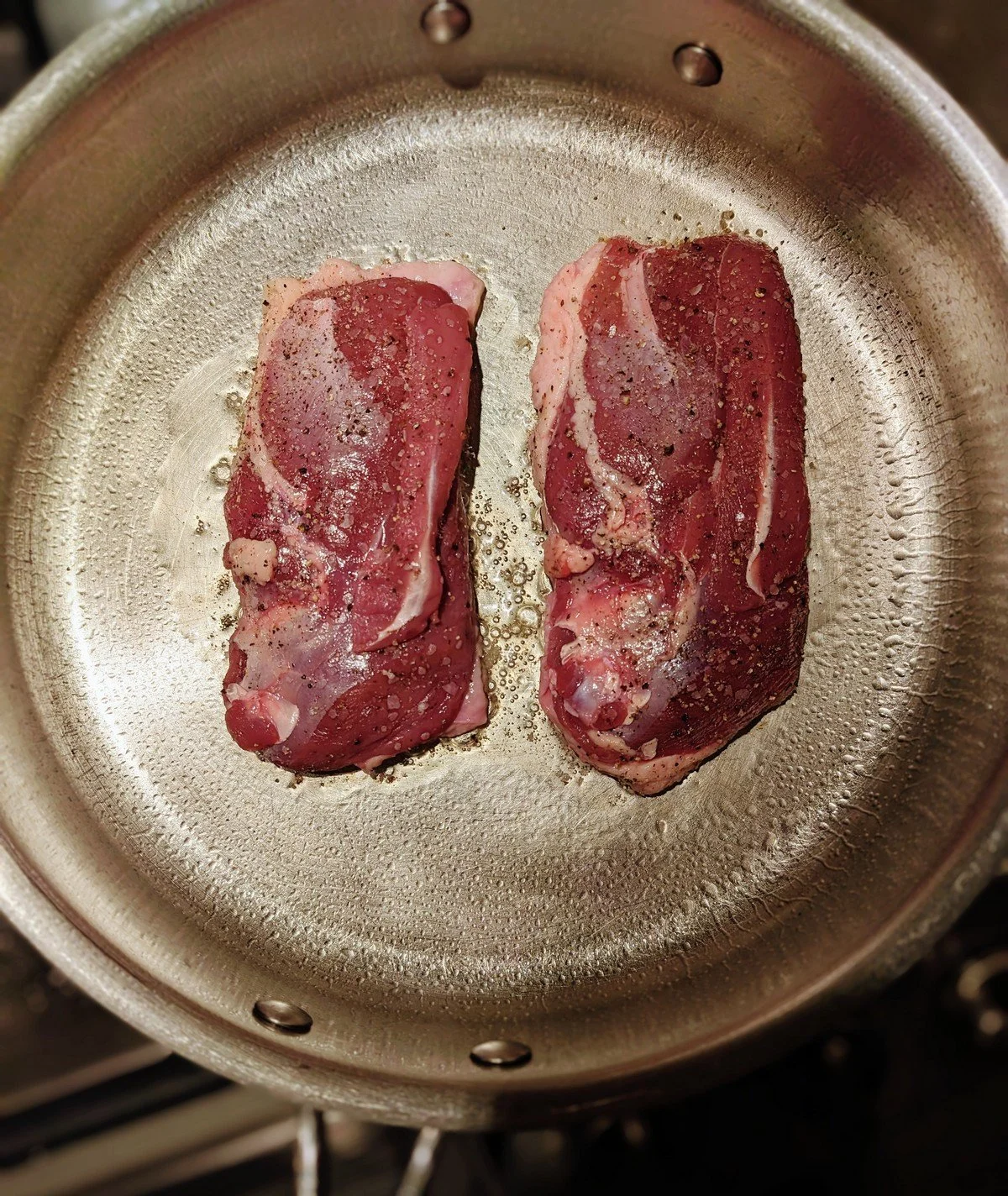 Fat rendering from duck breasts and pooling underneath.