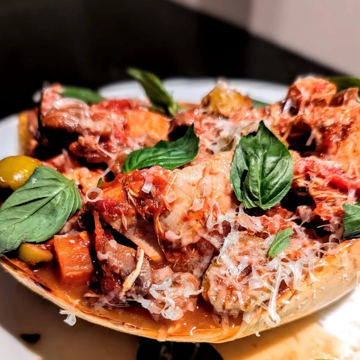 Roasted spaghetti squash topped with turkey cacciatore, grated Parmesan, and fresh basil leaves, served as a healthy low-carb option