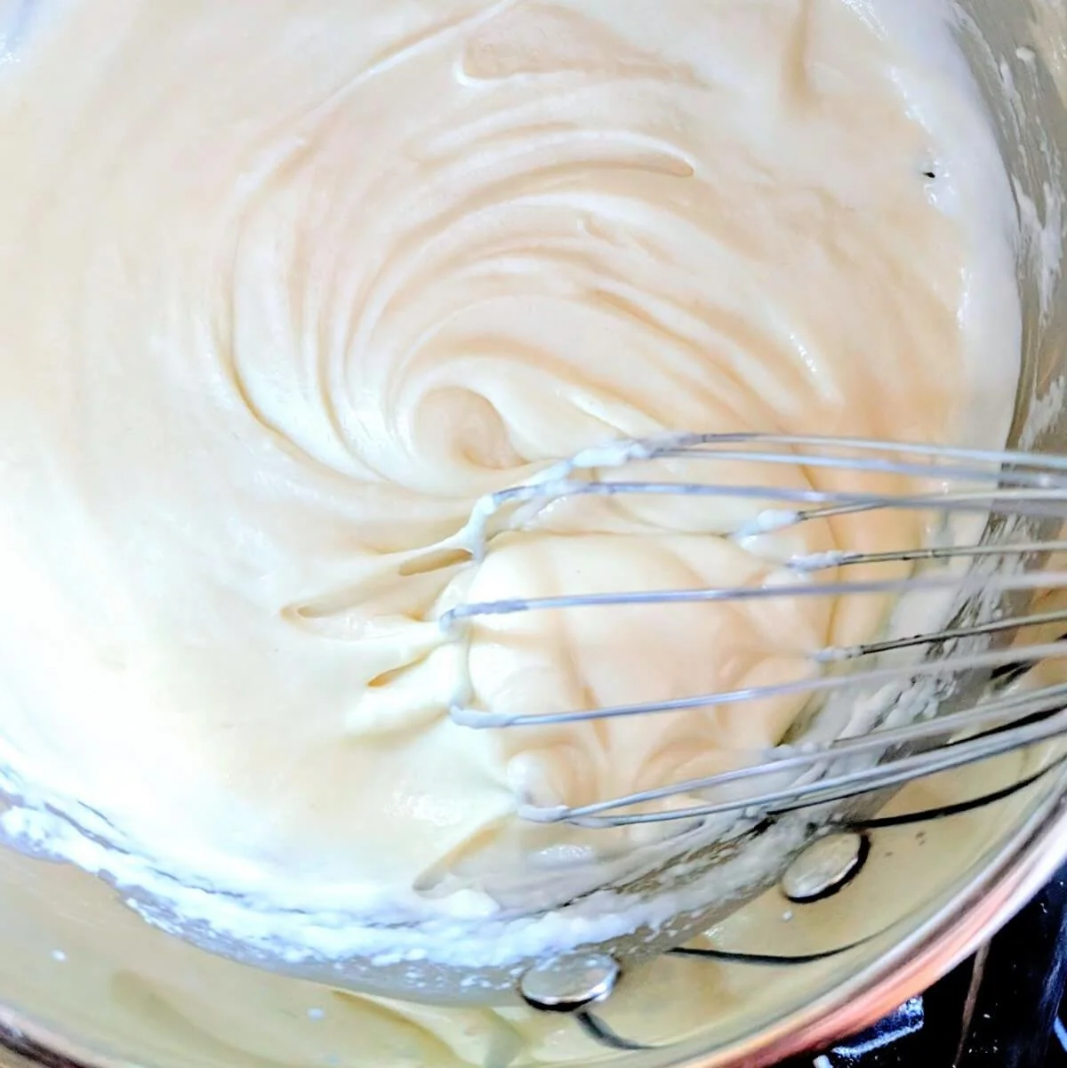 White sauce recipe being prepared by whisking in a saucepan