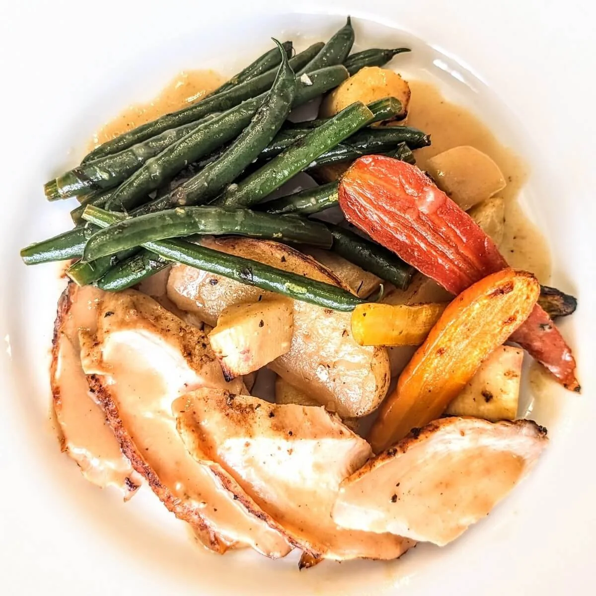 Sliced roast turkey breast with crispy skin and juicy meat on a wooden cutting board before being served as a Christmas dinner main