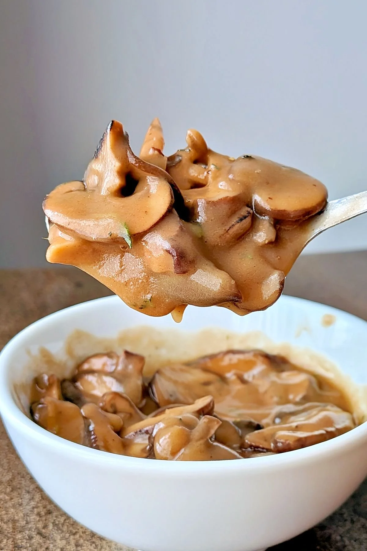 Spoonful of vegetarian mushroom gravy over a white bowl