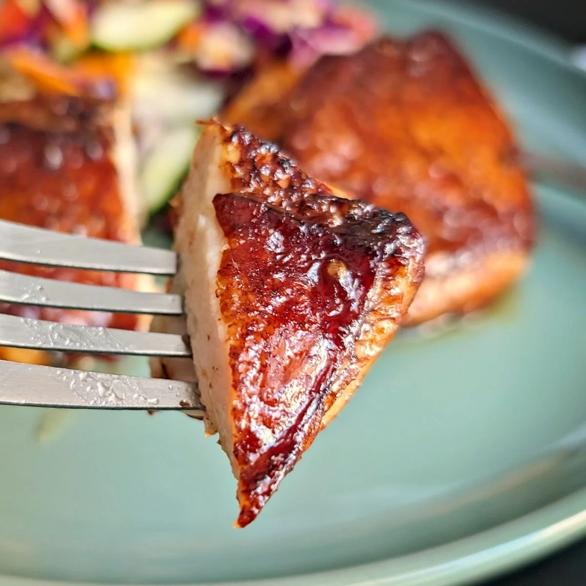 Close-up of air fryer soy balsamic chicken thigh showing juicy interior and caramelized glaze on a fork