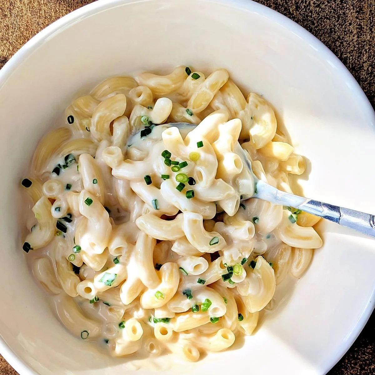 Bowl of pasta coated in creamy mornay sauce with fresh chives