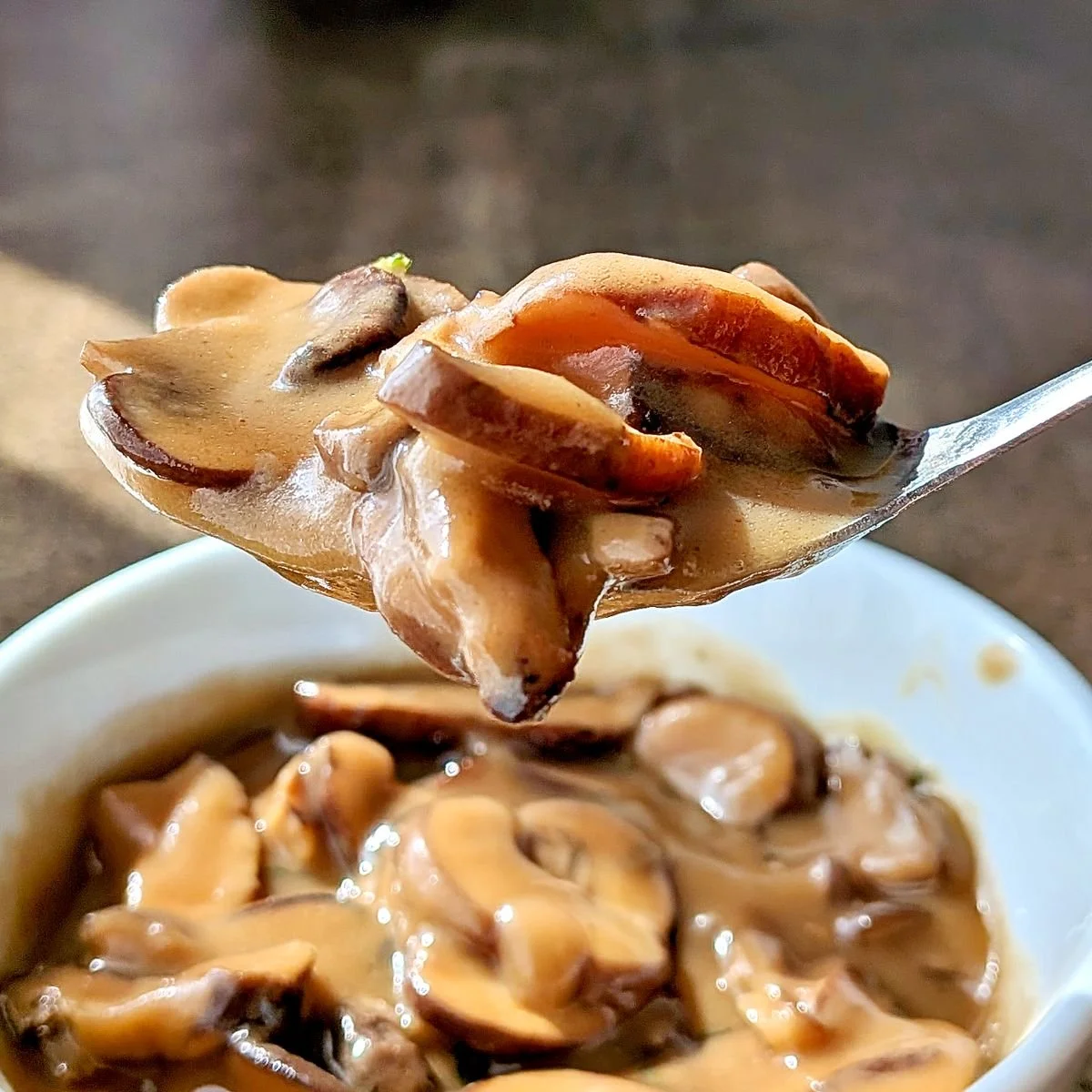 Spoonful of vegetarian mushroom gravy over a bowl