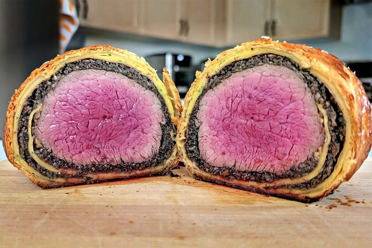 Medium-rare beef Wellington showing layers of mushroom duxelles, crêpe, and puff pastry