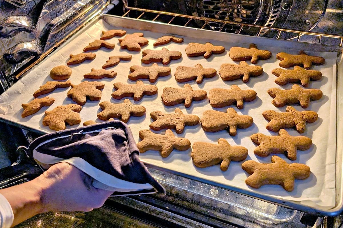 Gingerbread people baking on a parchment-lined sheet pan in the oven