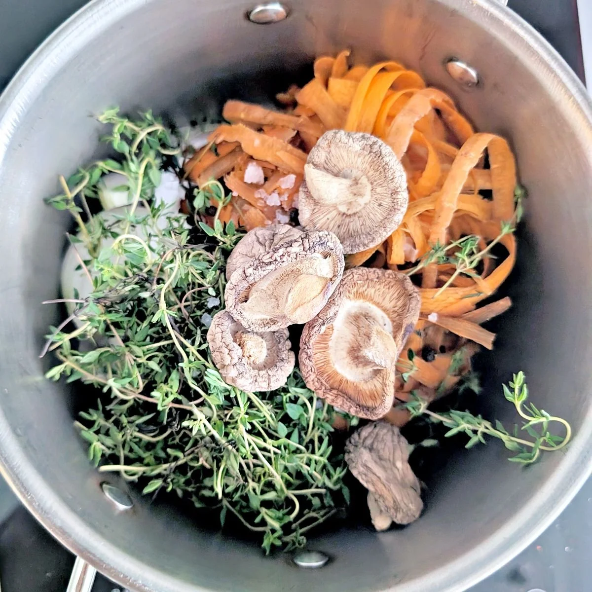 Dried mushrooms, carrot peels, thyme, and onion scraps in a pot before making homemade stock