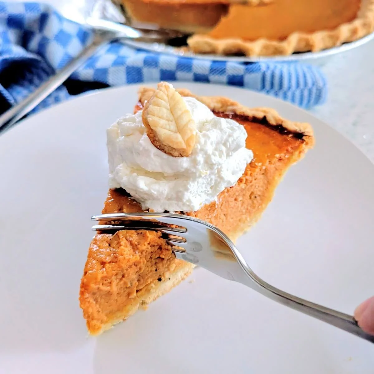 Homemade pumpkin pie with flaky crust, decorated with homemade whipped cream and a pie crust leaf