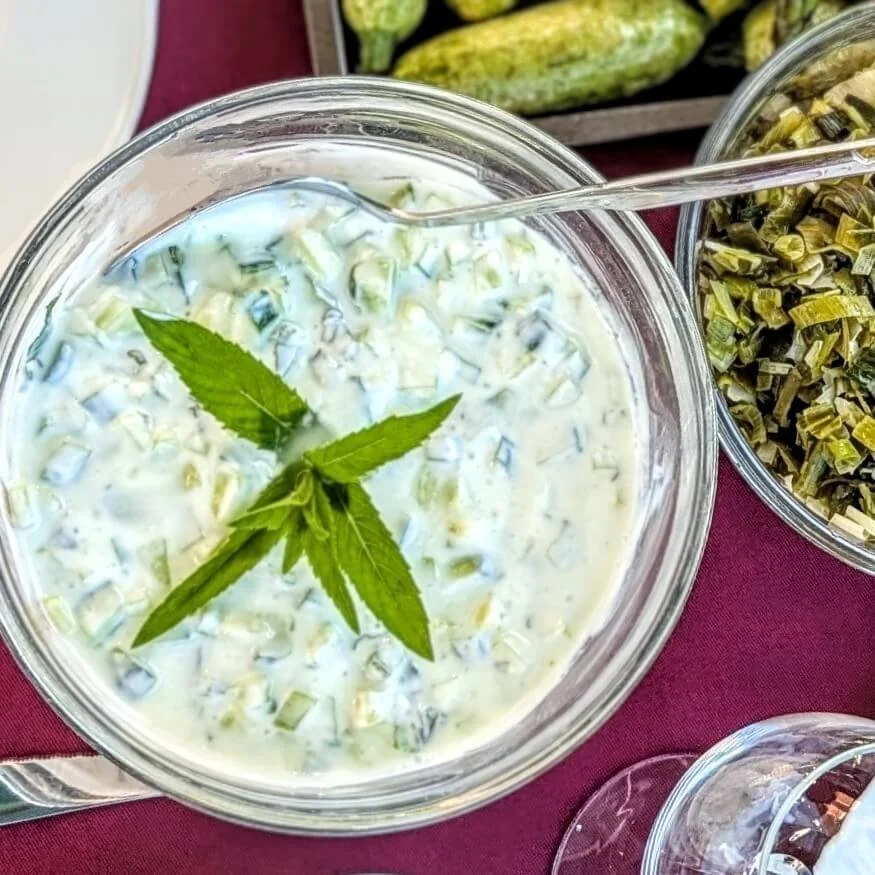 A bowl of Iraqi jajik sauce garnished with fresh mint on a table