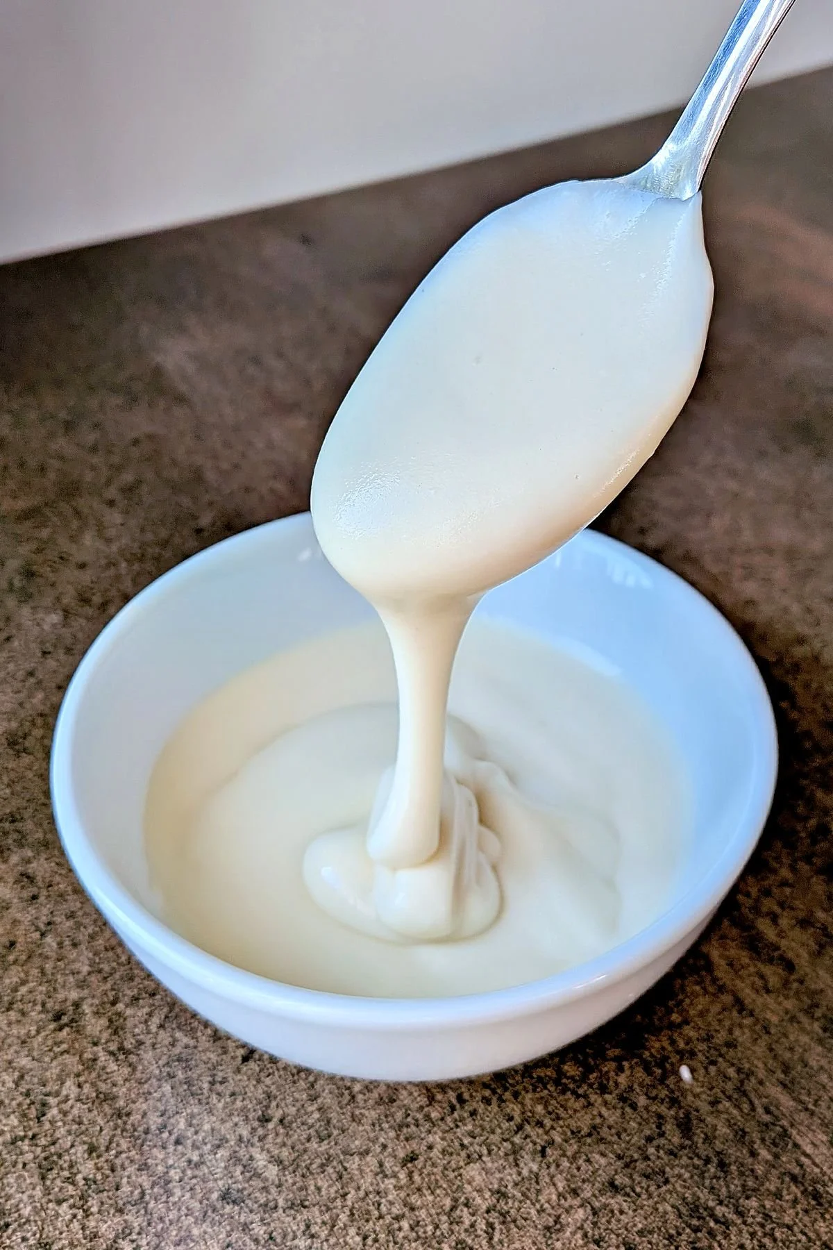 Mornay sauce being drizzled off a spoon into a bowl