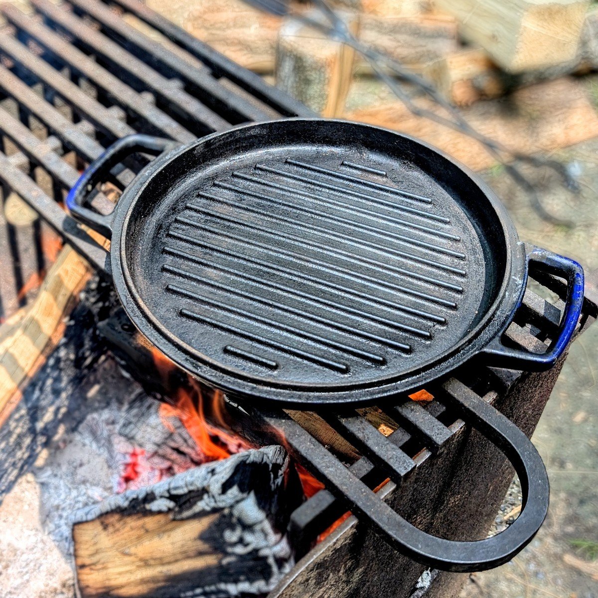 A cast-iron grill pan set over a campfire