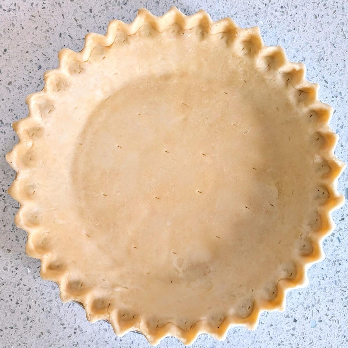 Unbaked homemade pie crust on a countertop, shaped and ready for blind-baking