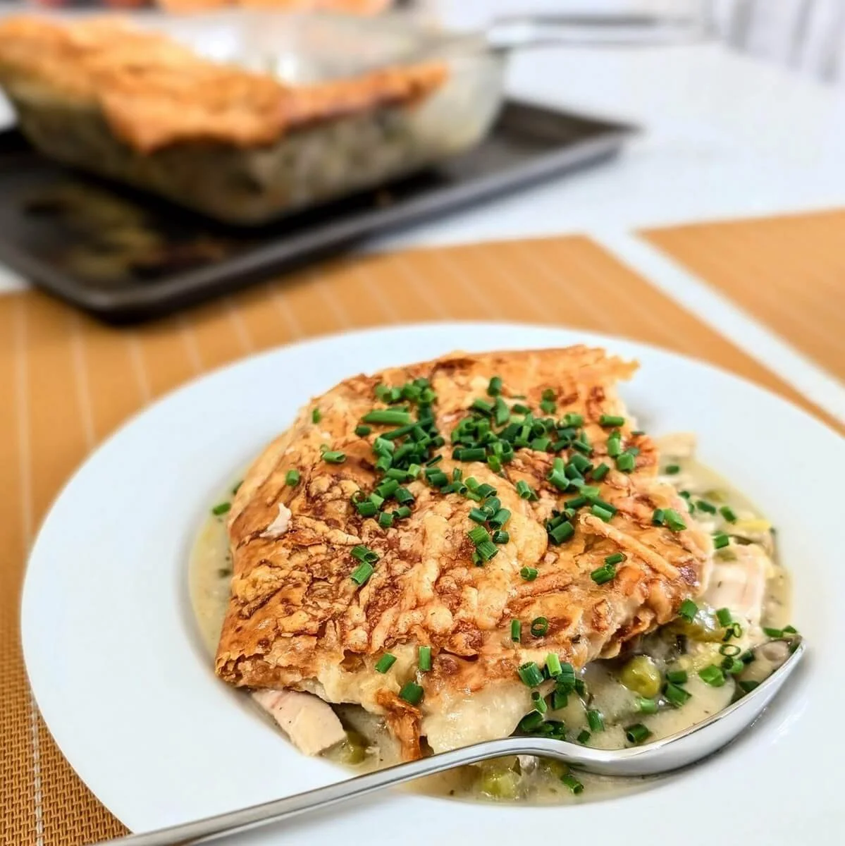Rotisserie chicken pot pie with puff pastry crust, creamy velouté filling, and chives