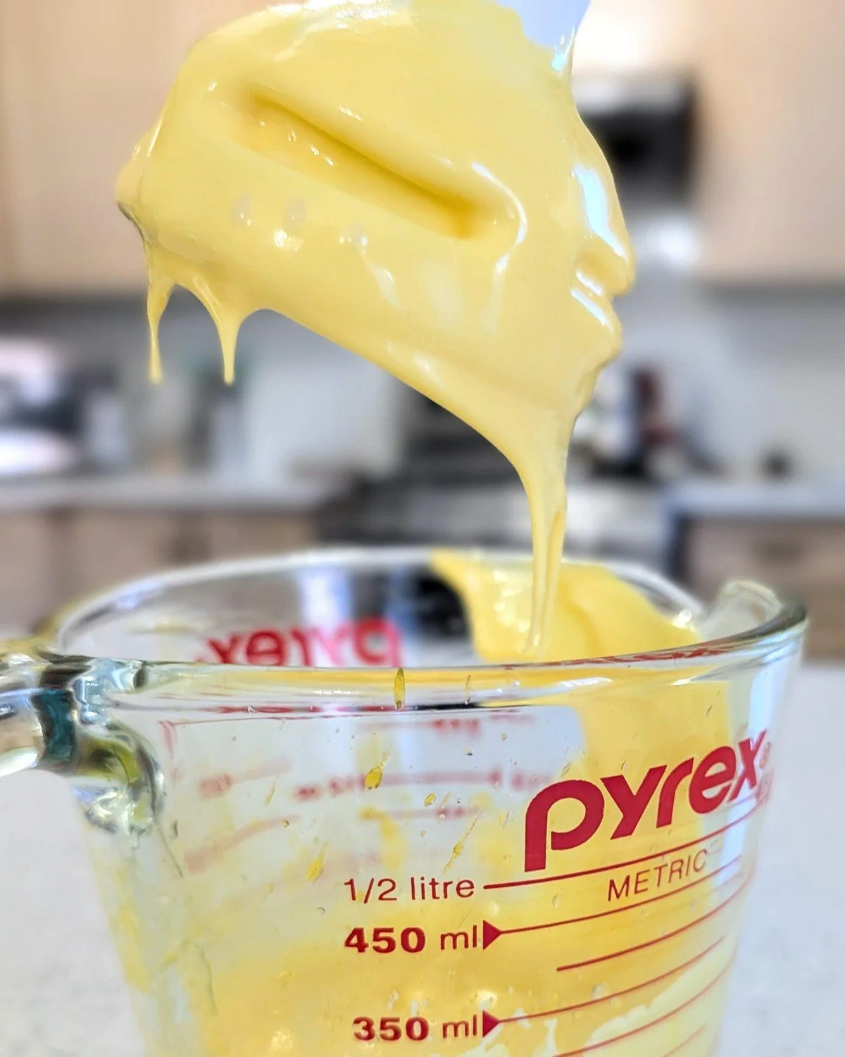An immersional blender being lifted out of a container for making hollandaise, a modern chef’s approach to making the classic French mother sauce