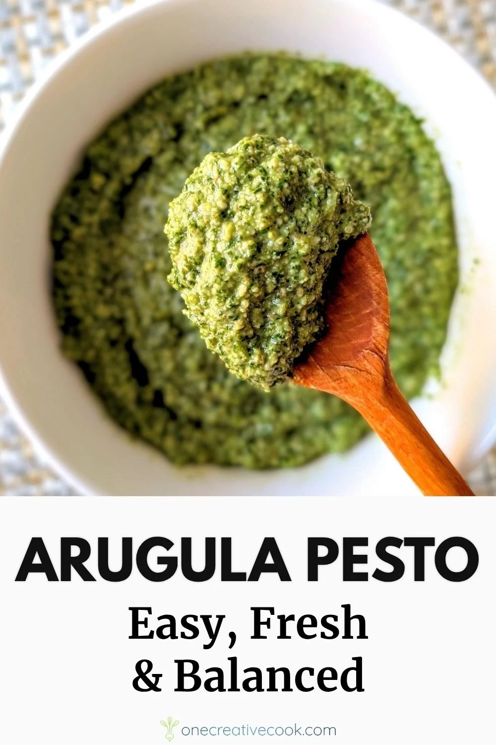 Arugula basil walnut pesto recipe on wooden spoon above white bowl with thick texture and bright green color