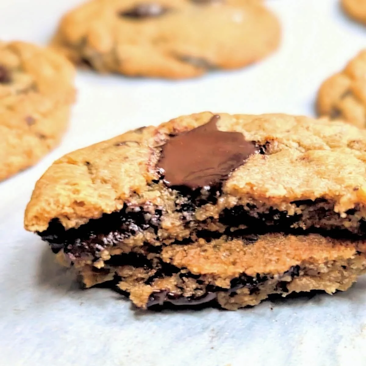 Broken chocolate chunk cookie with gooey dark chocolate on a tray of freshly baked salted cookies