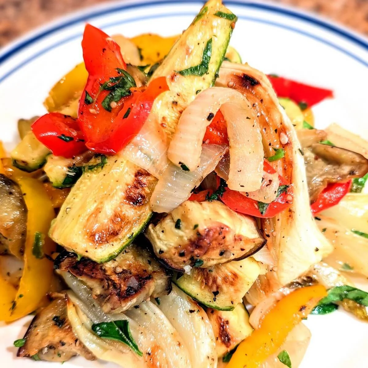 Roasted zucchini, onion, fennel, eggplant, and bell peppers marinated in vinaigrette and served on a white platter with herbs for Christmas dinner
