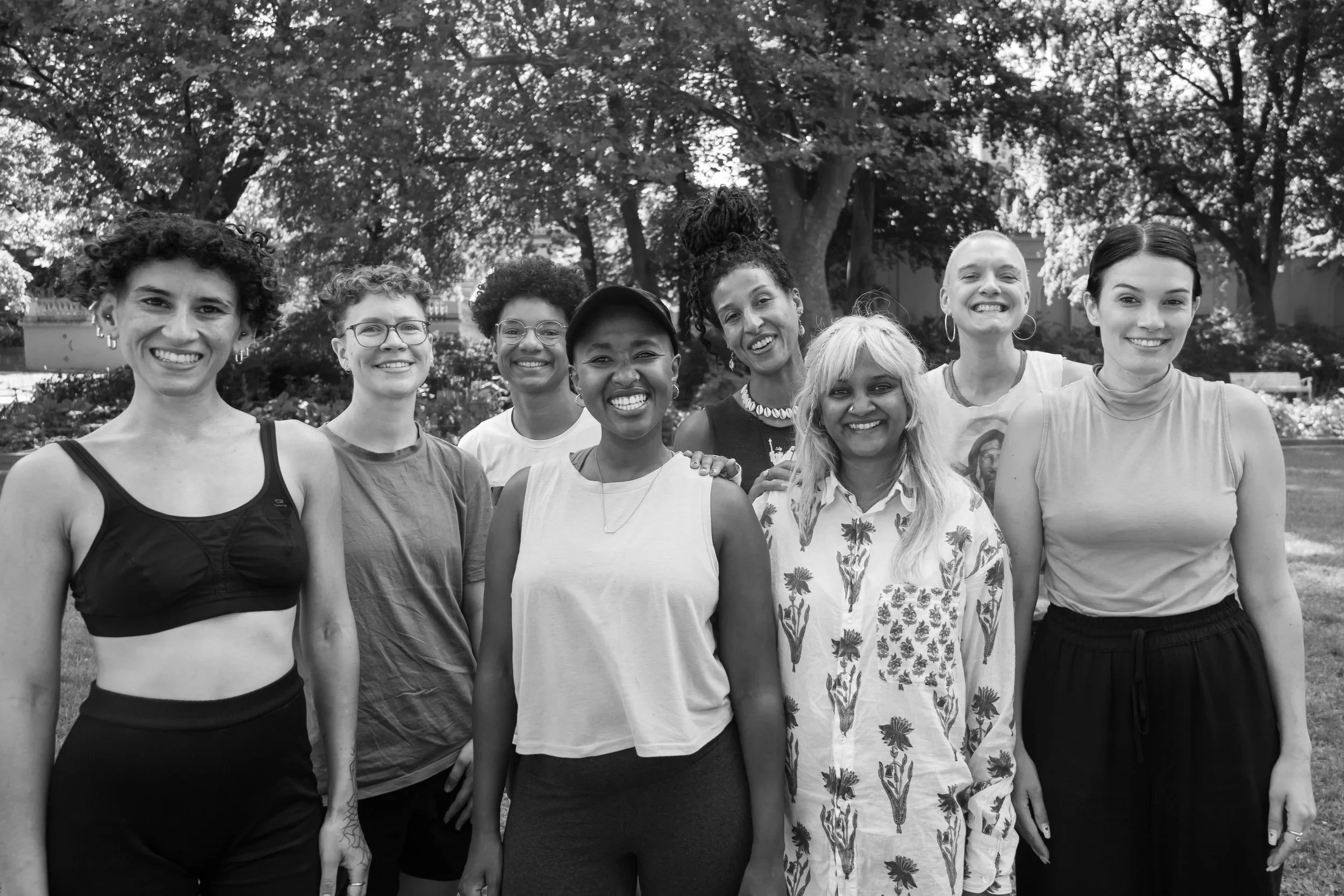 Group of diverse women smiling outdoors in a park with trees in the background