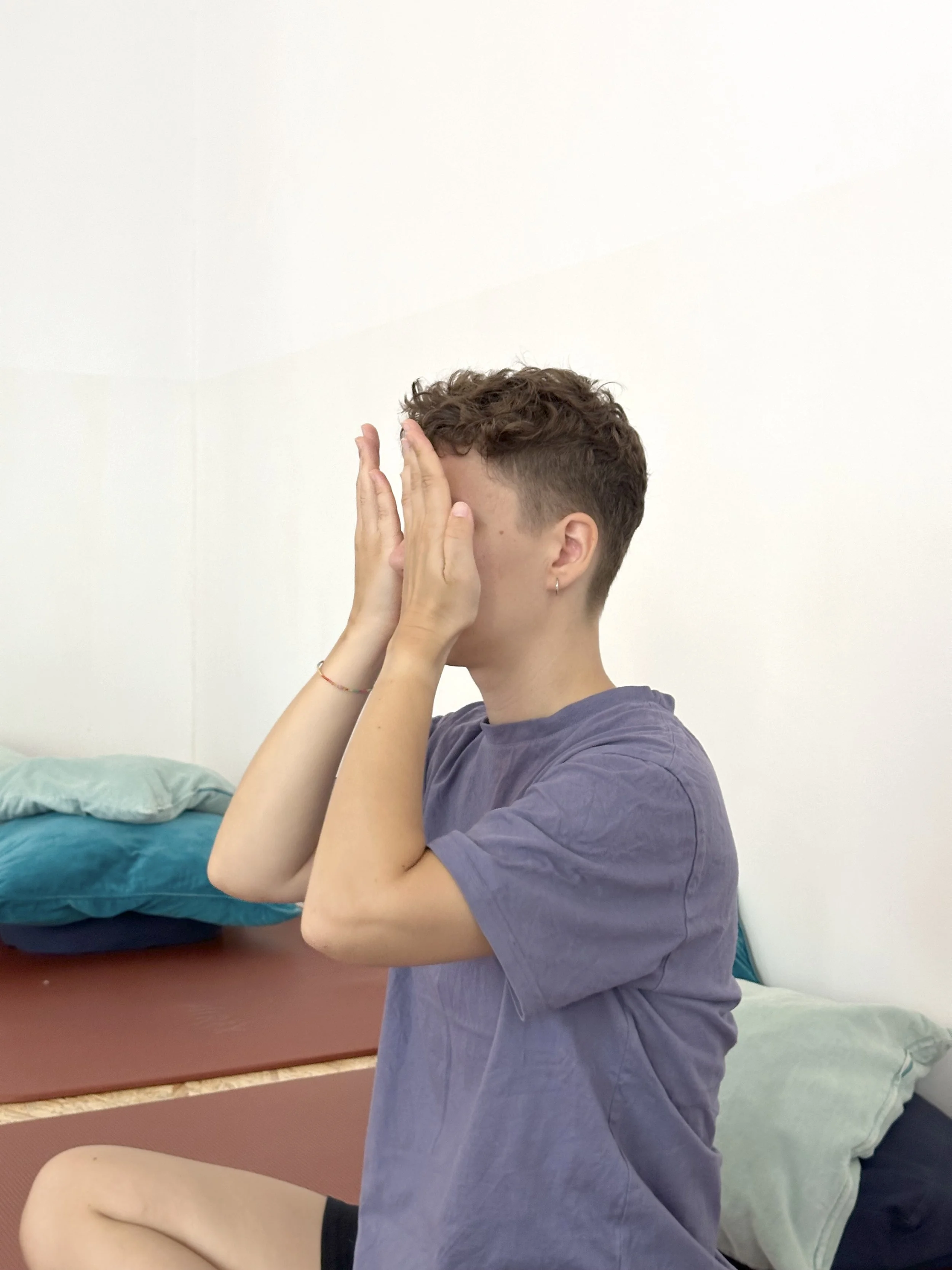 Picture of a person holding their hands in front of their face. Yoga with Sangeeta: Online yoga courses and in person classes in Berlin, making yoga an everyday practice of healing and self care for everybody.