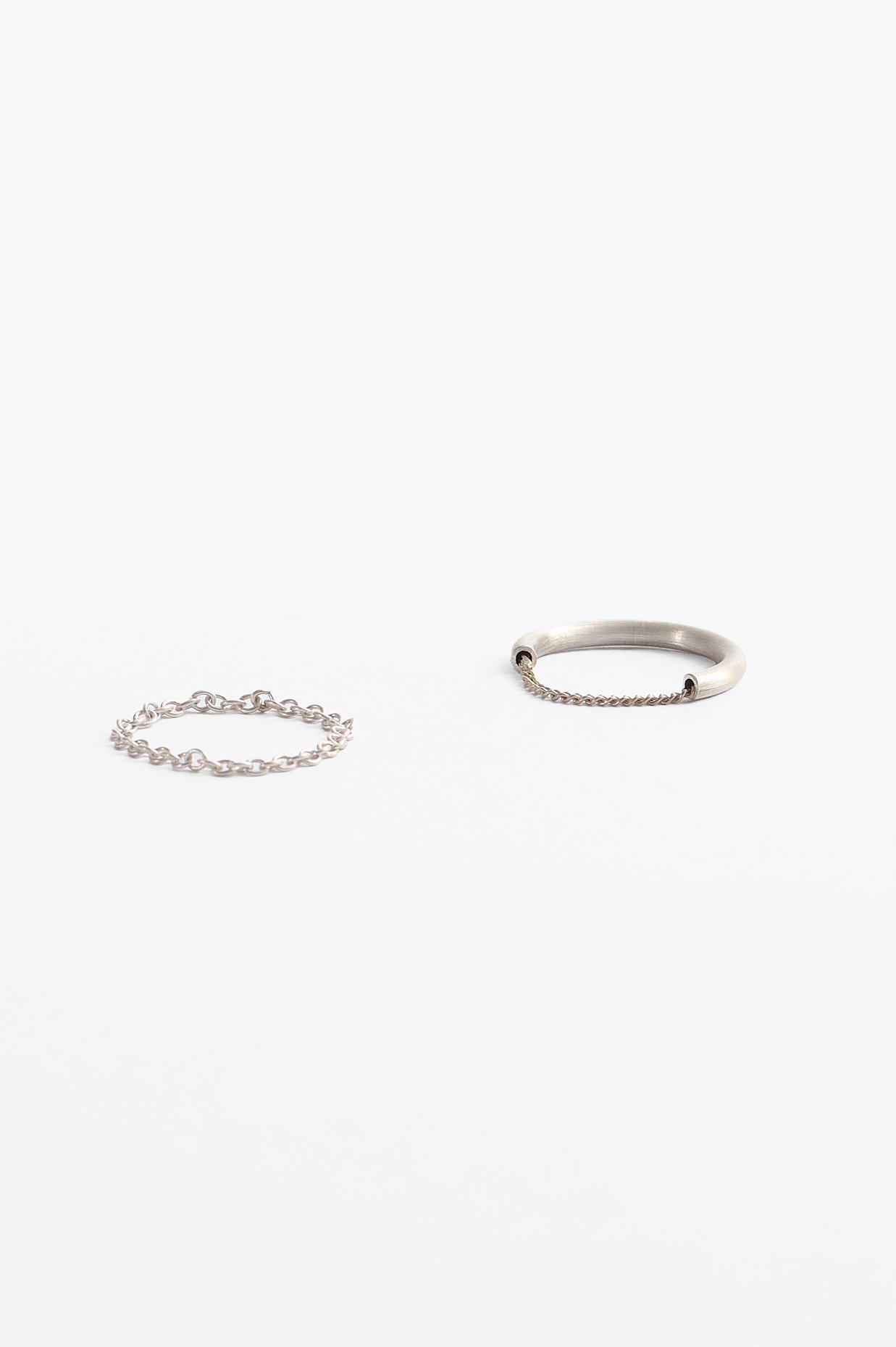 Katie Collins, Melting (left), sterling silver, 2.2 x .2cm, approx. size S, 2025 and What runs deep (right), sterling silver, 2.2 x .25cm, approx. size O, 2025. Photography: Ross Coulter.