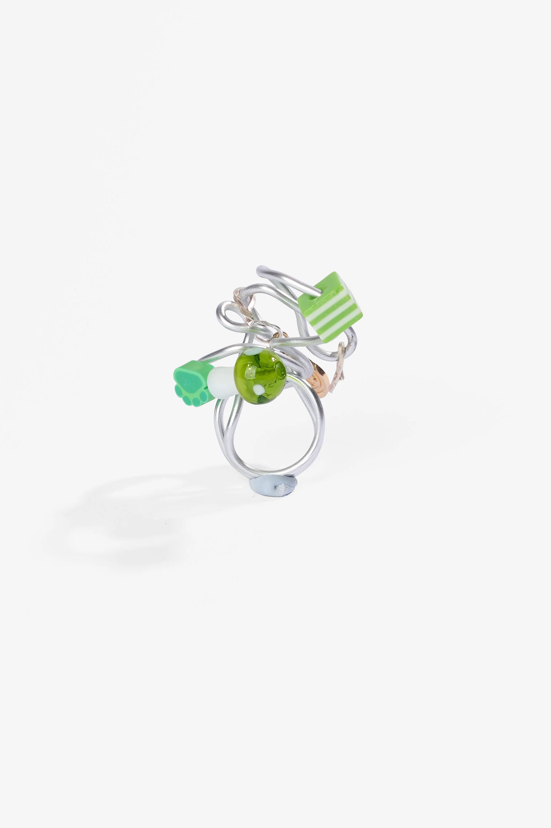 Roma Turnbull-Coulter, Green ring, sterlig silver wire, aluminium wire, metal trinket, plastic and glass beads, 2026, $75. Photography: Ross Coulter