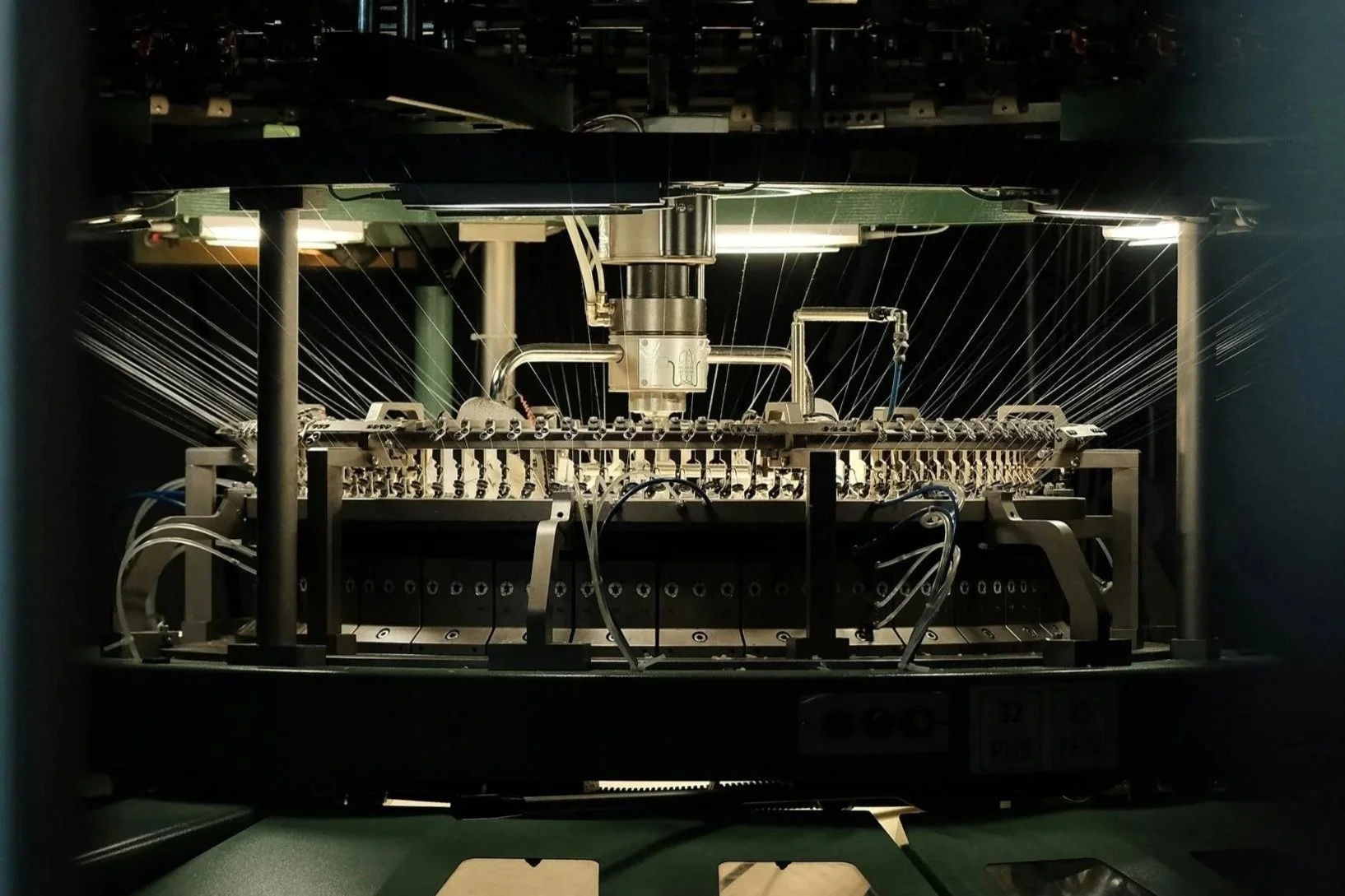 Un dispositif industriel complexe avec des câbles, des éléments métalliques et des tubes, dans une pièce sombre, probablement une machine ou un équipement technique.