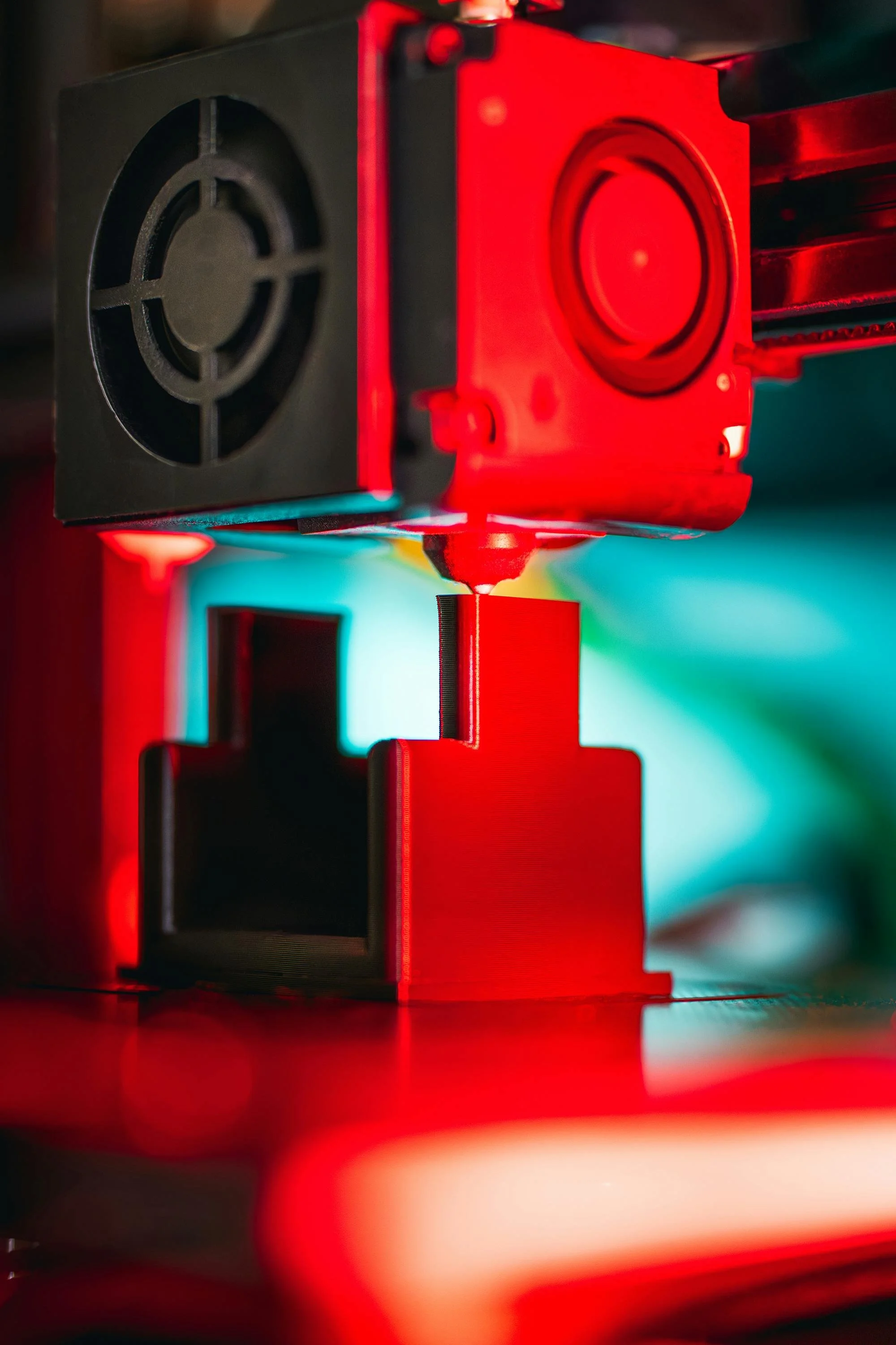 Une imprimante 3D en cours d'impression, avec un filament rouge."}