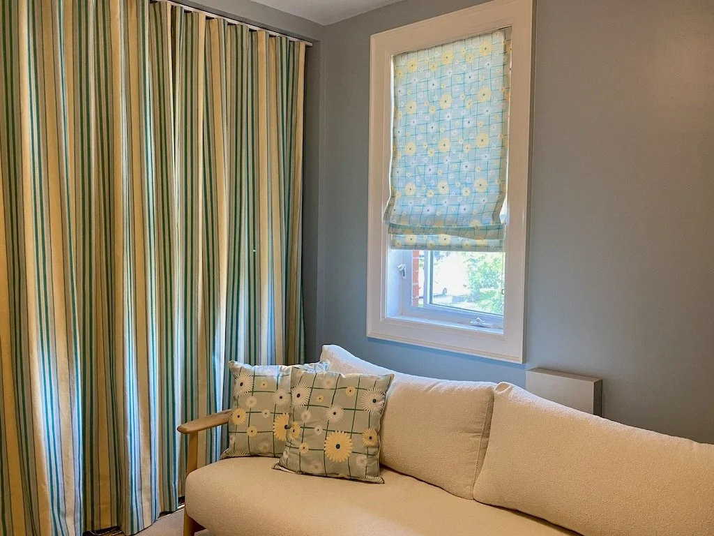 Picture of office with throw pillows and roller blind in daisy pattern and matching striped curtains